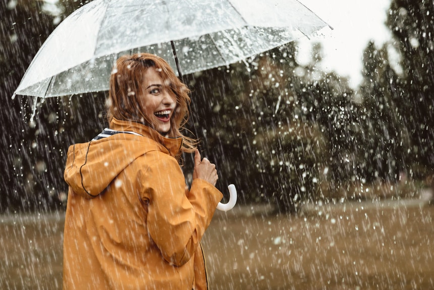 Vrouw buiten die een paraplu in de regen vasthoudt
